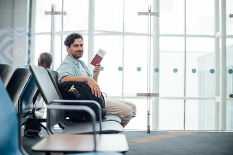 The guy with the backpack is sitting at the airport. Stock Photos