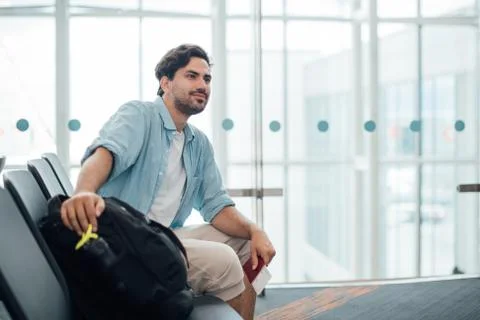 The guy with the backpack is sitting at the airport. Stock Photos