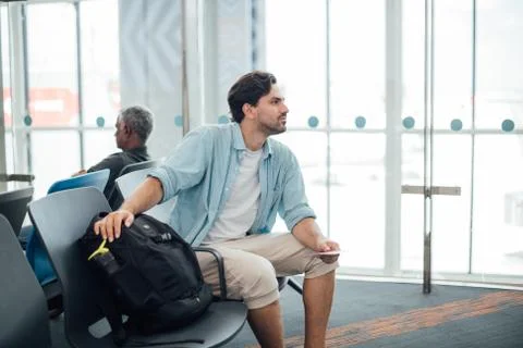 The guy with the backpack is sitting at the airport. Stock Photos