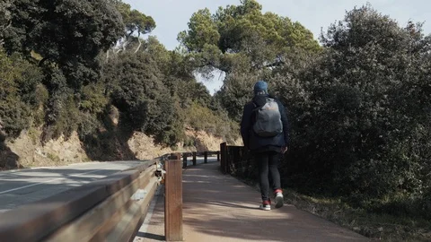 The guy with backpack walks on a footpath along the road in Barcelona Stock Footage 101270248