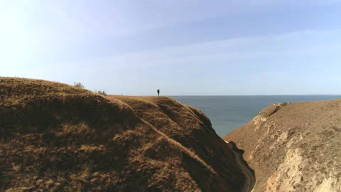 The guy with bag standing on the mountain top against the seascape Vídeos de archivo 143042410