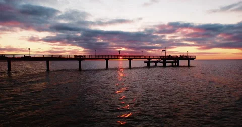 Guy balancing on pier handrail sunset reflection Stock-Footage 153515891
