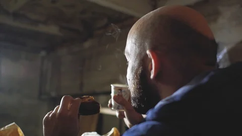 A guy with a bald head and a beard is drinking a hot drink from a disposable Stock Footage 102942198