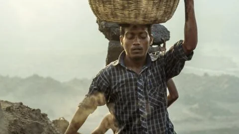 A guy with a basket of coal on his head, climbs up the coal mine. Jharia Stock Photos