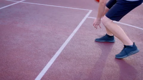 The guy basketball player dribbles the ball between the legs in the open area Stock Footage 240656889