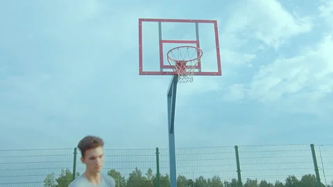 Guy basketball player is training to throw the ball into the basket on the open Stock Footage 237934765