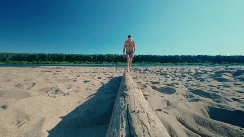 The guy on the beach approaches the log and drags it to another place. Stock Footage 313496799