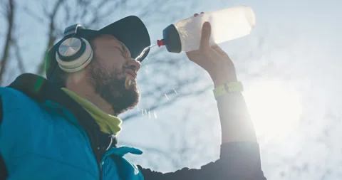 Guy with beard and cap on head drinks water from water bottle. The man has Stock Footage 215827098