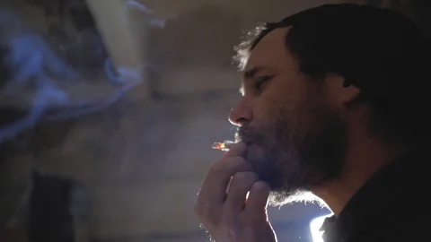 A guy with a beard and a knitted hat pulls out a cigarette.marijuana smoking Stock Footage 102942301