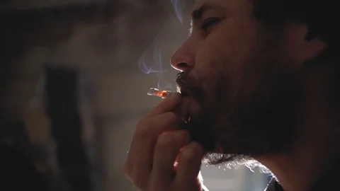 A guy with a beard and a knitted hat is smoking a cigarette.marijuana smoking Stock Footage 102942808