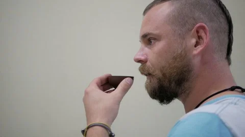 A guy with a beard and a mohawk drinking tea from a bowl Stock Footage 99573681