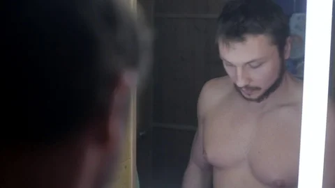 A guy with a beard and mustache dissatisfied looks in the mirror Stock Footage 102673923