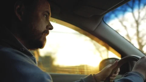 The guy with the beard and mustache is driving a car at sunset Stock Footage 103217541