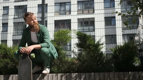 Guy with beard and mustache in green suit with longboard, concept of freedom Stock Footage 147473880