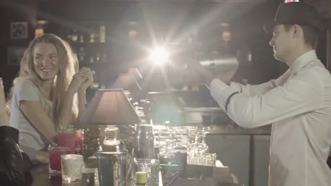 A guy with a beard and two girls watching as the bartender prepares their Stock Footage 76949896