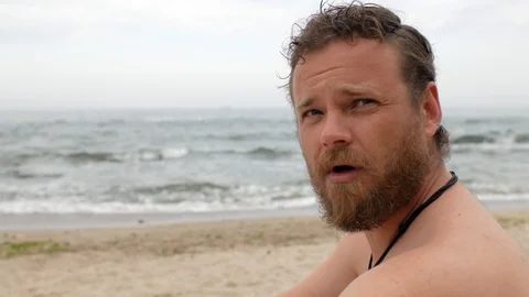 Guy with a beard on the background of the sea is combing his beard with a comb Vídeos de archivo 108113091