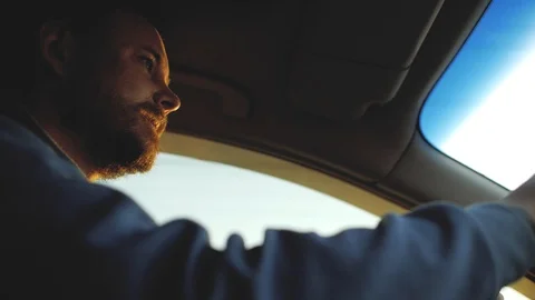 A guy with a beard with beautiful eyes is driving a car. sun rays in the wind Stock Footage 103568609