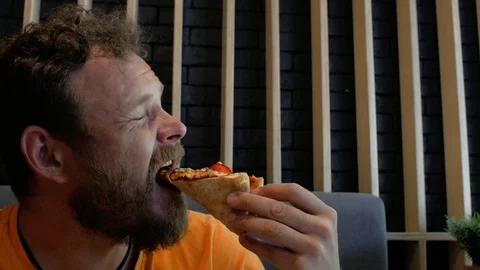 The guy with the beard bites hot pizza and frowns.4k. 4k video Stock Footage 111383390