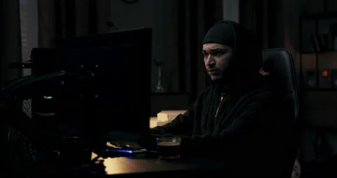 Guy with beard in black sweatshirt and cap is typing on computer keyboard. There Stock Footage 214708155