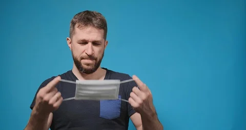 Guy with beard puts disposable medical mask on and breathes 스톡 동영상 128094594