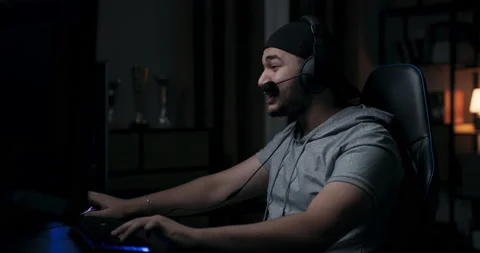 Guy with beard is sitting in room and playing online games. Man in gray T-shirt Stock Footage 214153165