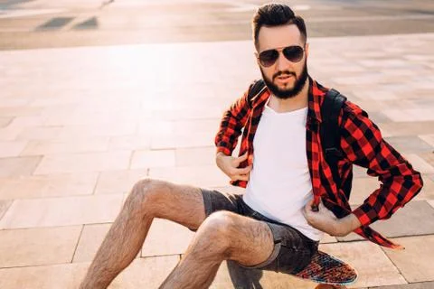 Guy with a beard with a skateboard at sunset. Stock Photos