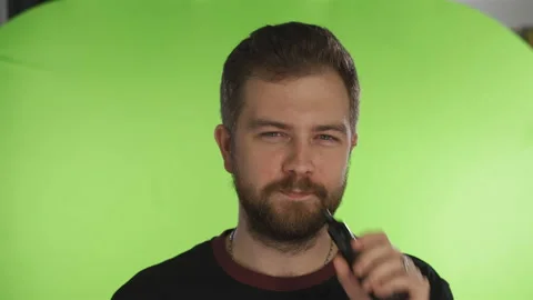 Guy with a beard smokes an e-cigarette in the studio on an isolated background Stock Footage 164372602
