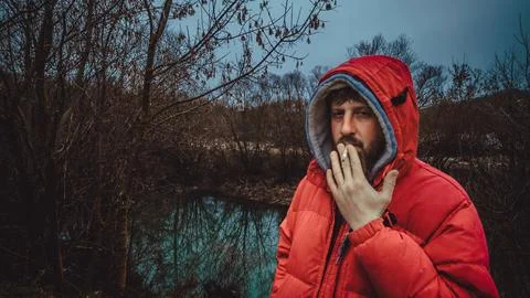A guy with a beard smokes by the river Stock Photos