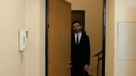 A guy with a beard in a suit and tie is standing outside the door and talking Vídeos de archivo 111725086