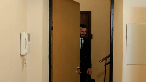A guy with a beard in a suit and tie speaks standing, then closes the door Stock Footage 111725100