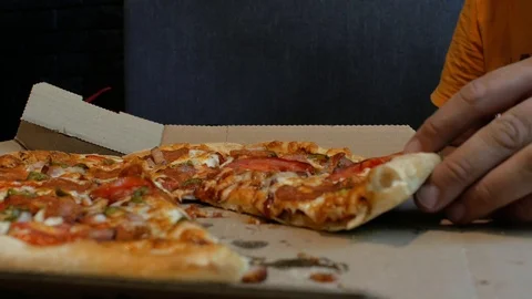 The guy with the beard takes a piece of pizza in his hand and bites the pizza Stock Footage 111383401