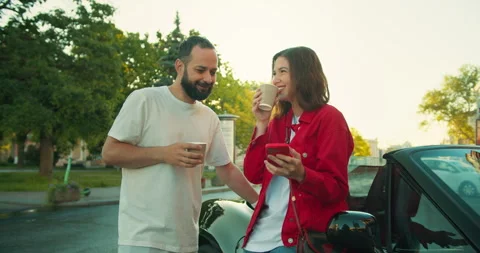 A guy with a beard in a white T-shirt talks to a girl in a red jacket during a Stock Footage 280599441