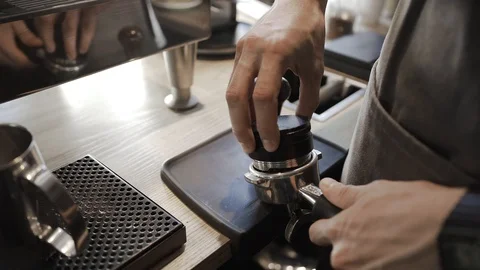 Guy behind a bar counter in a cafe, tamping ground coffee using a press Stock Footage 129261686