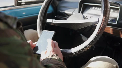 The guy behind the wheel in the car looks at the news on the phone Stock-Footage 103138295