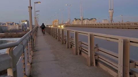 Guy on a bicycle is driving on a bridge Stock Footage 77414336