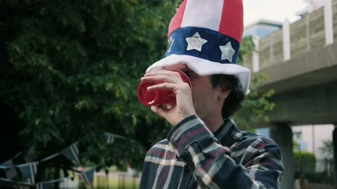 Guy with big 4th of July hat drinking from plastic cup Video stock 133613774