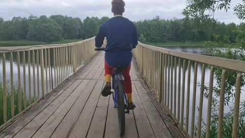 The guy with the bike on the bridge over the river. To ride a bike. Video stock 156715852