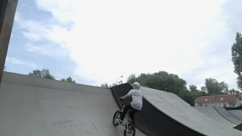 Guy on the bike performs a trick in skate park 库存影片 103031339