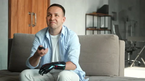 Guy with bio limb prothesis switches television with remote Stock Footage 157534369