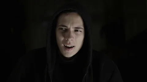 A guy with a bipolar disorder laughs and gets angry in dramatic lighting Stock Footage 120597409