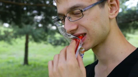 The guy bites a red crab stick (imitation crab). Outdoor, real time, natural lig Stock Footage 102331725