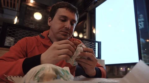 Guy biting a big burger near window ad mocap lightbox Stock Footage 90289867