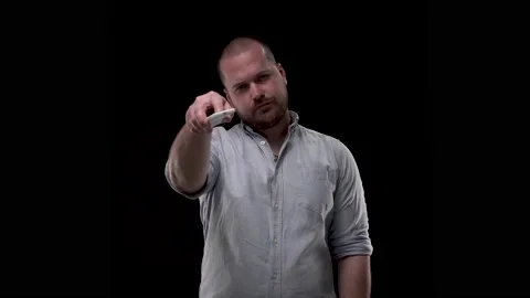 Guy on black background using the remote control switches channels or programs Stock Footage 132302630