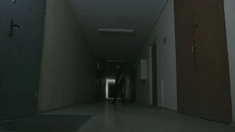 A guy in black clothes and a black cap stands in a dark corridor 스톡 동영상 155905340