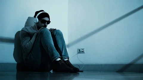 Guy in black glasses sitting on the floor wearing headphones Stock Footage 102112452