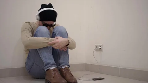 Guy in black glasses sitting on the floor wearing headphones Видео 102112460