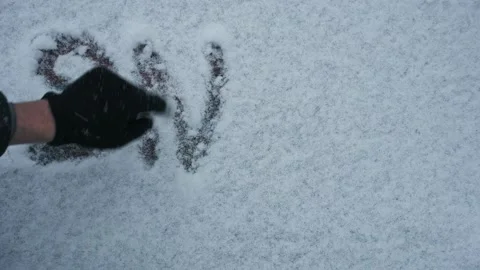 Guy in black gloves writes the word snow on freshly fallen snow Stock Footage 149339546
