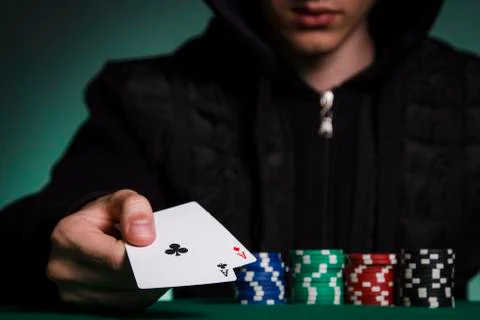 A guy in a black jacket holds a pair of aces against a pile of poker chips Stock Photos