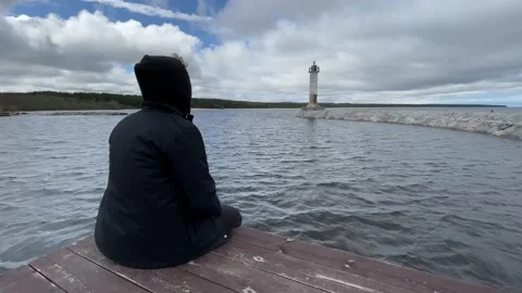 A guy in a black jacket is sad and looks into the distance next to the sea light Stock-Footage 205832993
