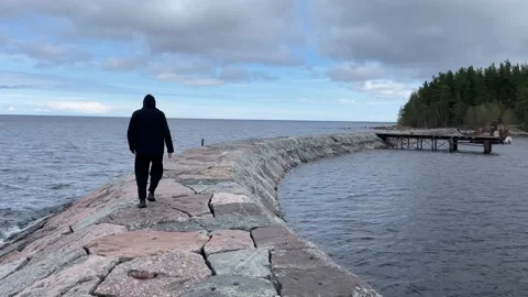 A guy in a black jacket is sad and looks into the distance next to the sea light Stock-Footage 205833013